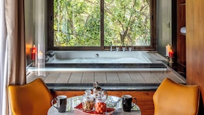Un baño moderno con un ventanal grande, una bañera y dos sillones orientados hacia la ventana.