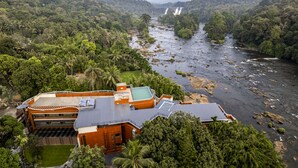 Un hotel con piscina, paneles solares y vistas a un río y una cascada.