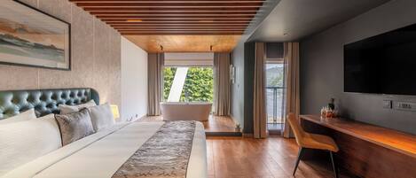 A modern hotel room with a large bed, a bathtub, a desk, and a TV.