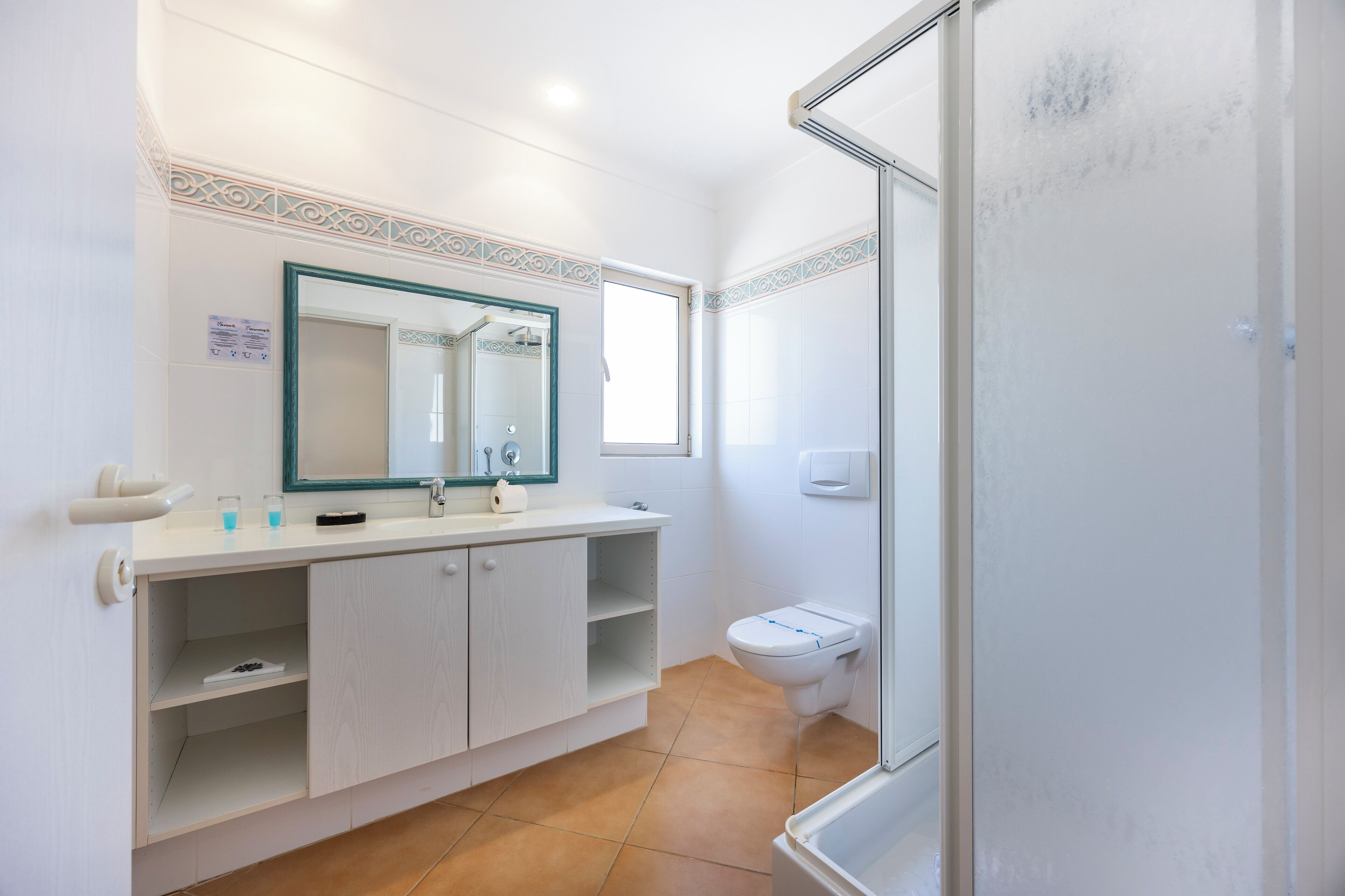 A bathroom with a white vanity, a mirror, a toilet, and a shower area.
