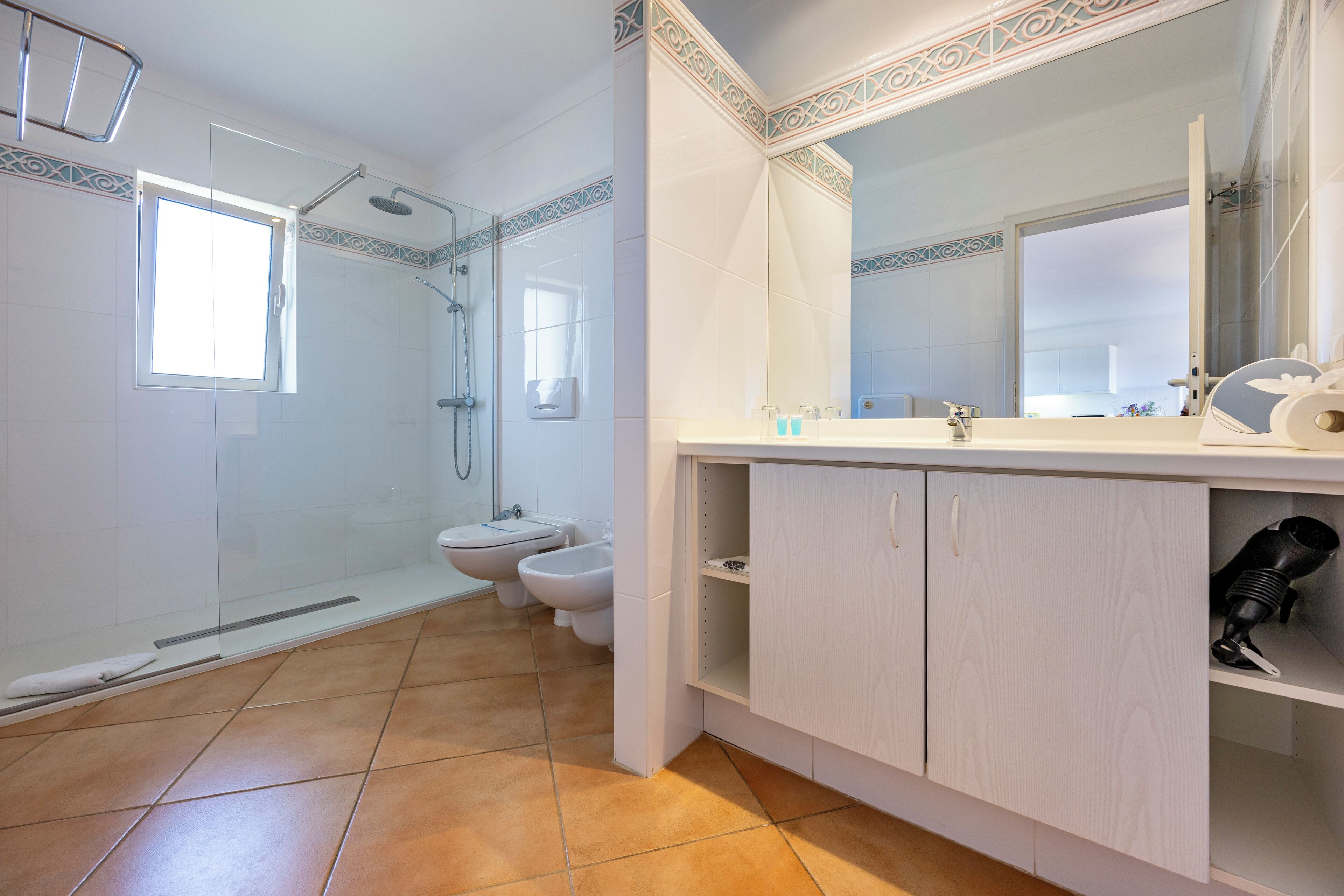 A modern bathroom with a glass-enclosed shower, a toilet, and a sink with a mirror.