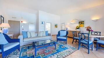 A modern living room with a sofa, armchairs, a coffee table, and a dining area with chairs and a table.