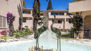 Una fontana con due statue di cigno in un cortile circondato da edifici.