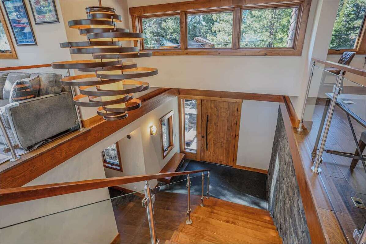 A modern interior with a spiral staircase, wooden beams, and large windows offering a view of the outdoors.