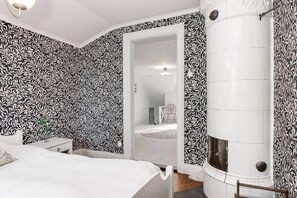 Cozy retreat with a large fireplace, white bed, and stylish wallpaper.