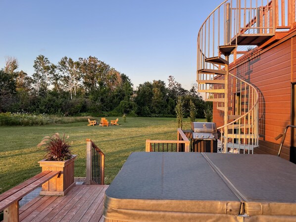 Een terras met een hottub, buitenmeubels en een spiraaltrap naar een houten terras.