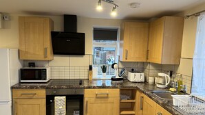 Una cocina moderna con armarios de madera, microondas integrado, tostadora y hervidor.