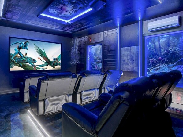 A home theater with a large screen, reclining chairs, and a wall-mounted projector. - Themed 8BR: Game Room • 2 Theaters • Pool & Spa (Kissimmee)