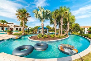 A swimming pool with three inflatable rings, palm trees, and lounge chairs. - Themed 8BR: Game Room • 2 Theaters • Pool & Spa (Kissimmee)
