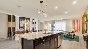 A spacious kitchen with a large island, dark cabinetry, and a modern chandelier. - Themed 8BR: Game Room • 2 Theaters • Pool & Spa (Kissimmee)