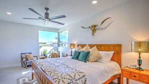 A bedroom with a large bed, a ceiling fan, a mounted cow skull, and a view of the outdoors. - Charming Tucson Vacation Rental: 2 Mi to Downtown (Tucson)