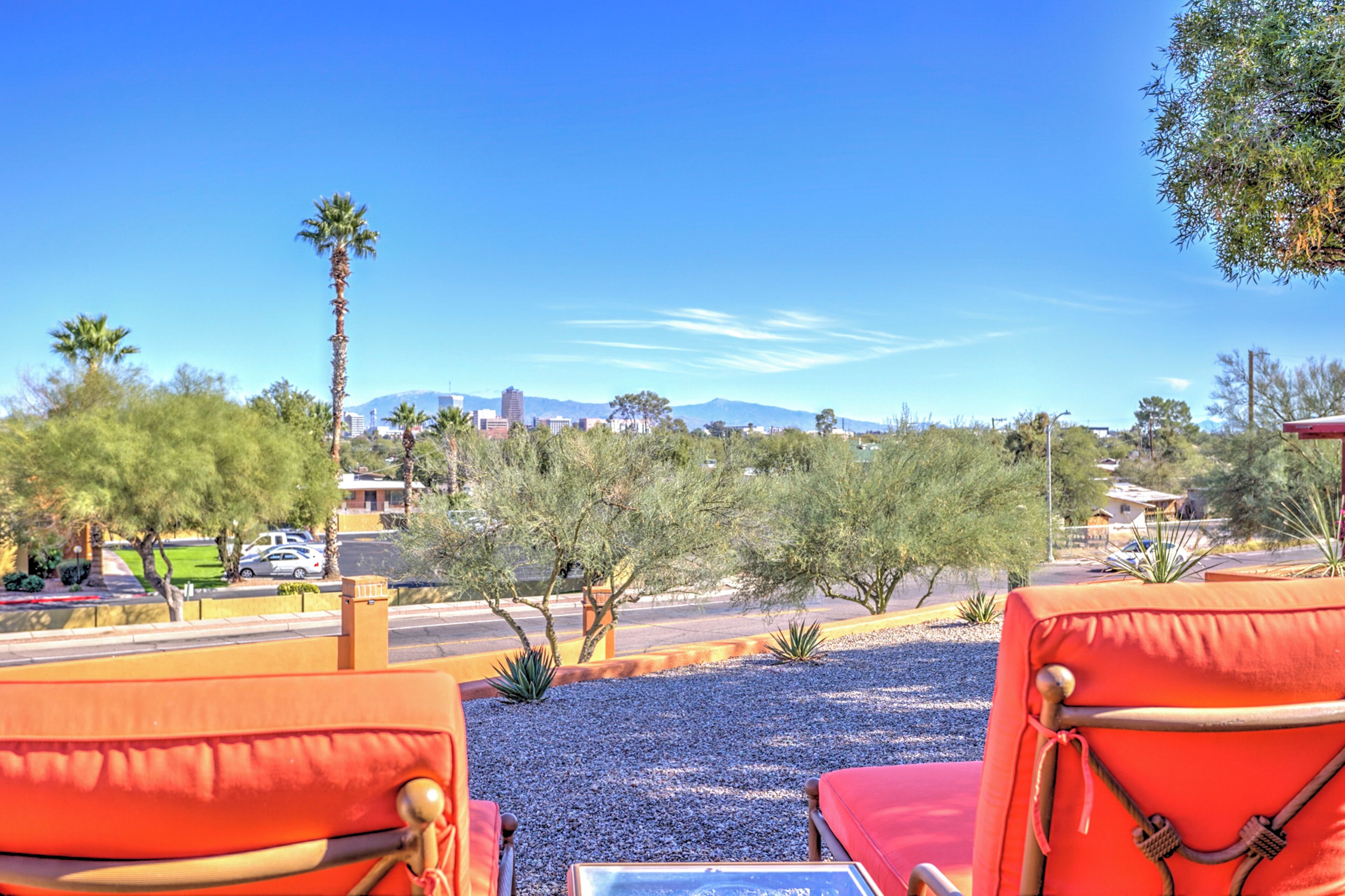 A view from a balcony with red chairs, a clear blue sky, and distant mountains.