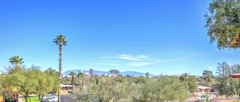 A view from a balcony with red chairs, a clear blue sky, and distant mountains.