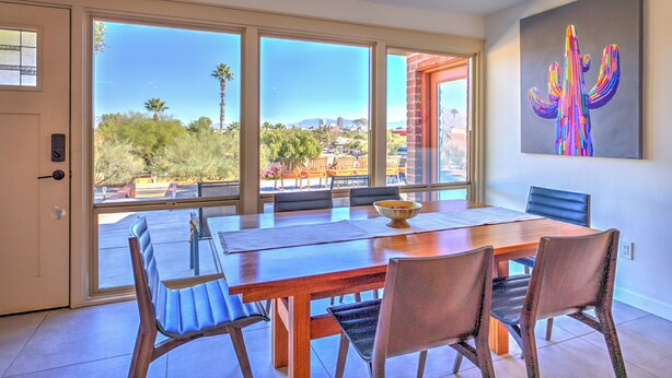A dining area with a large table, chairs, and a view of the city through large windows. - Charming Tucson Vacation Rental: 2 Mi to Downtown (Tucson)