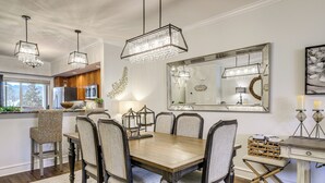 A dining area with a wooden table, upholstered chairs, and hanging crystal chandeliers. - Elegant Pigeon Forge Condo w/ Golf Course View! (Pigeon Forge)