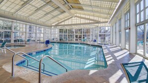 An indoor swimming pool with clear glass walls, a tiled floor, and a high ceiling with skylights. - Elegant Pigeon Forge Condo w/ Golf Course View! (Pigeon Forge)