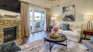 A living room with a stone fireplace, a chandelier, a sofa, and a coffee table. - Elegant Pigeon Forge Condo w/ Golf Course View! (Pigeon Forge)