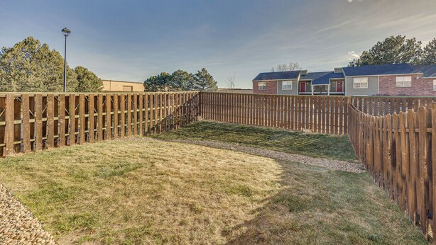 A fenced backyard with a grassy area, a paved path, and a street lamp. - Colorado Springs Townhome ~ 7 Mi to Downtown! (Colorado Springs)