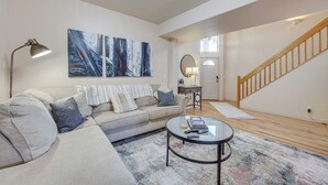 A living room with a sofa, coffee table, and artwork on the wall. - Colorado Springs Townhome ~ 7 Mi to Downtown! (Colorado Springs)