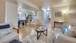 A spacious living room with a wooden floor, a glass coffee table, and a sofa with a patterned cushion. - Colorado Springs Townhome ~ 7 Mi to Downtown! (Colorado Springs)