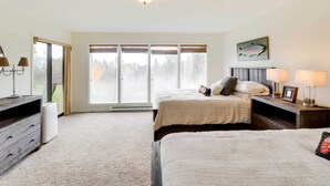 A bedroom with two beds, a large window with a view, a ceiling light, and a fish artwork on the wall.
