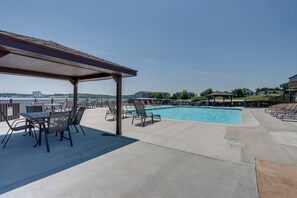 Un área de piscina con sillones de descanso y un espacio de estar cubierto.