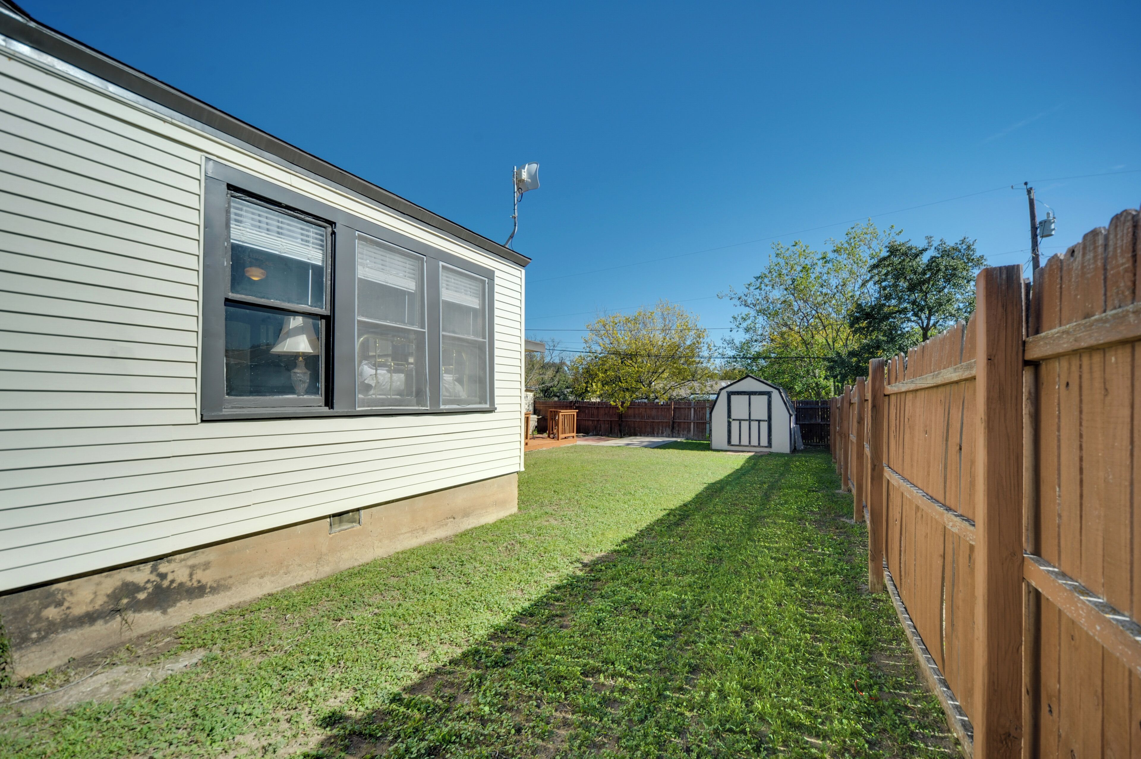 A house with a fenced backyard, a garage, and a clear blue sky.