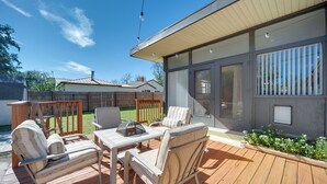 Une terrasse dotée de mobilier d’extérieur, d’une pergola et offrant une vue sur une maison.