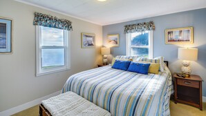A bedroom with a large bed, two bedside tables, and a window with curtains.