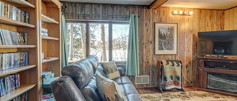 A living room with a leather sofa, a bookshelf, a fireplace, and a television.