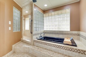 Une salle de bain dotée d’une baignoire sur pieds, d’un espace douche et de murs recouverts de carreaux décoratifs.