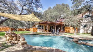 Un jardin avec une piscine, des marches en pierre, un patio couvert et une clôture en bois.