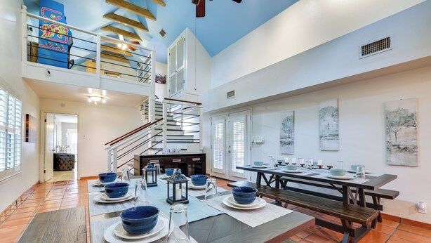 Une salle à manger spacieuse avec un haut plafond, un escalier et une vue sur l’extérieur.