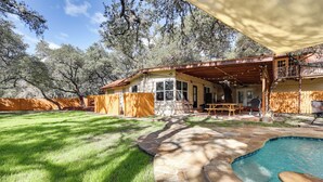Un jardin avec une piscine, une terrasse en bois et un espace patio couvert.