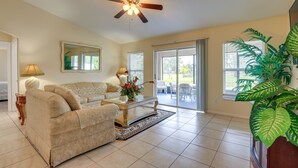 A spacious living room with a beige sofa, a coffee table, and a ceiling fan. - Pet-friendly Port St Lucie Home ~ 5 Mi to Marina! (Port Saint Lucie)