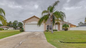 A single-story house with a garage, a front lawn, and a palm tree. - Pet-friendly Port St Lucie Home ~ 5 Mi to Marina! (Port Saint Lucie)