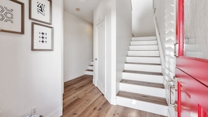 A staircase with white steps and a red door, leading to an upper floor. - Cardiff Panoramic Paradise - Stunning Ocean Views (Cardiff By The Sea)