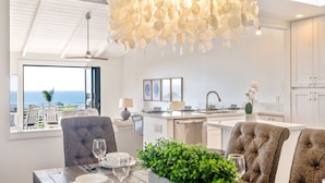 A modern kitchen with a central island, a dining area with a view of the ocean, and a ceiling fan. - Cardiff Panoramic Paradise - Stunning Ocean Views (Cardiff By The Sea)