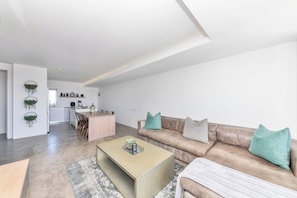 Ein modernes Wohnzimmer mit einer Ledersofa, einem Couchtisch und einer Küche im Hintergrund.