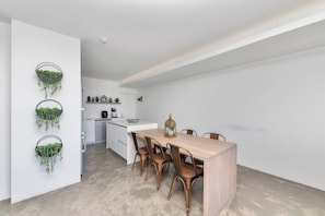 Eine moderne Küche mit weißen Schränken, einem Holztisch und drei Stühlen.