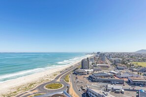 A coastal cityscape with a beach, roads, and buildings.