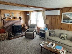 Ein gemütliches Wohnzimmer mit Kamin, einer Couch, einem Sessel und einem Couchtisch.