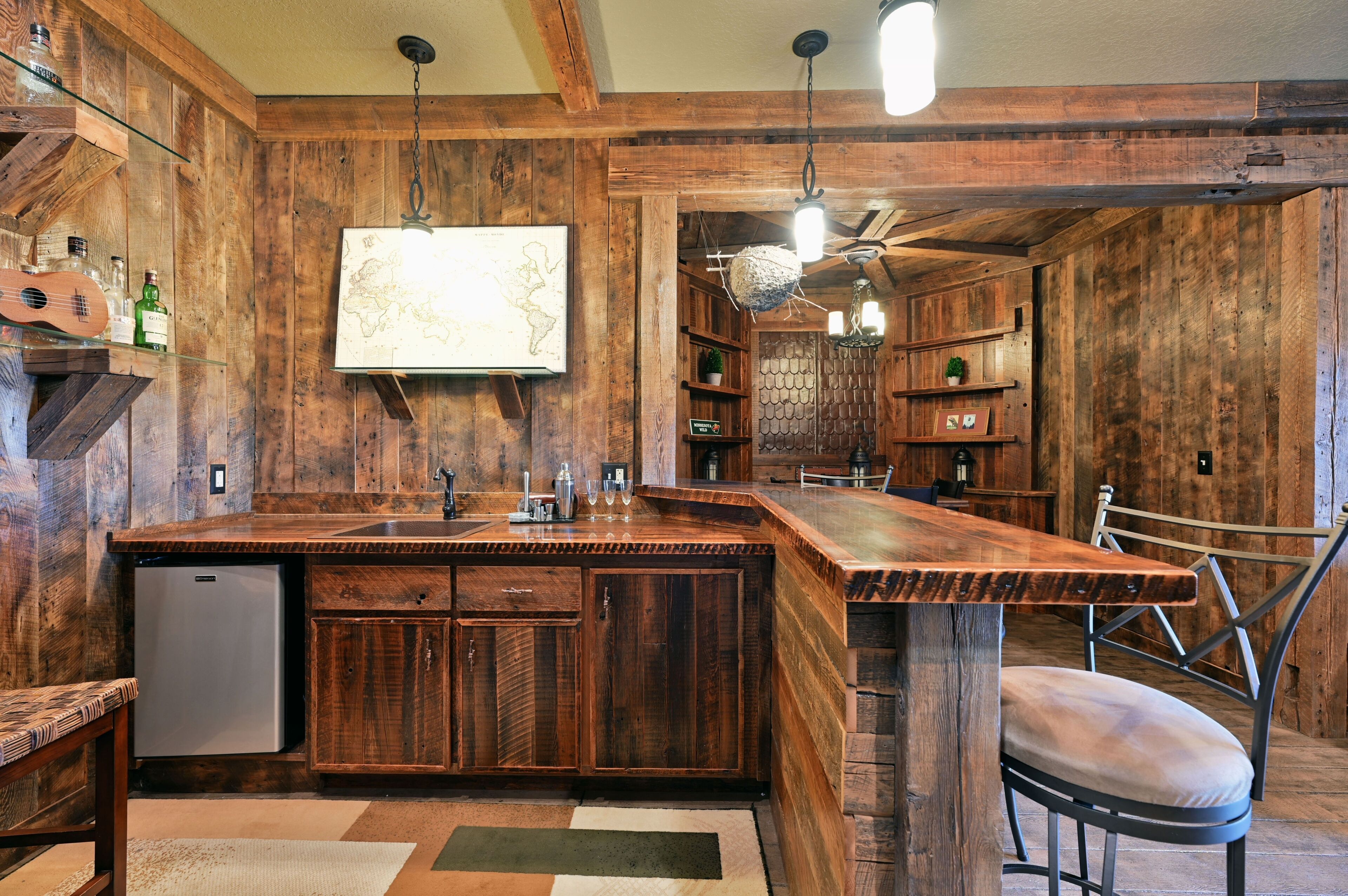 A rustic kitchen with wooden walls, a large island, and a ceiling fan.