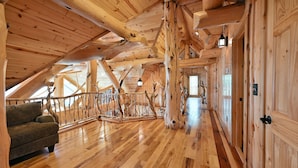 Un intérieur spacieux en bois, avec un plafond haut, un escalier en bois et un canapé.