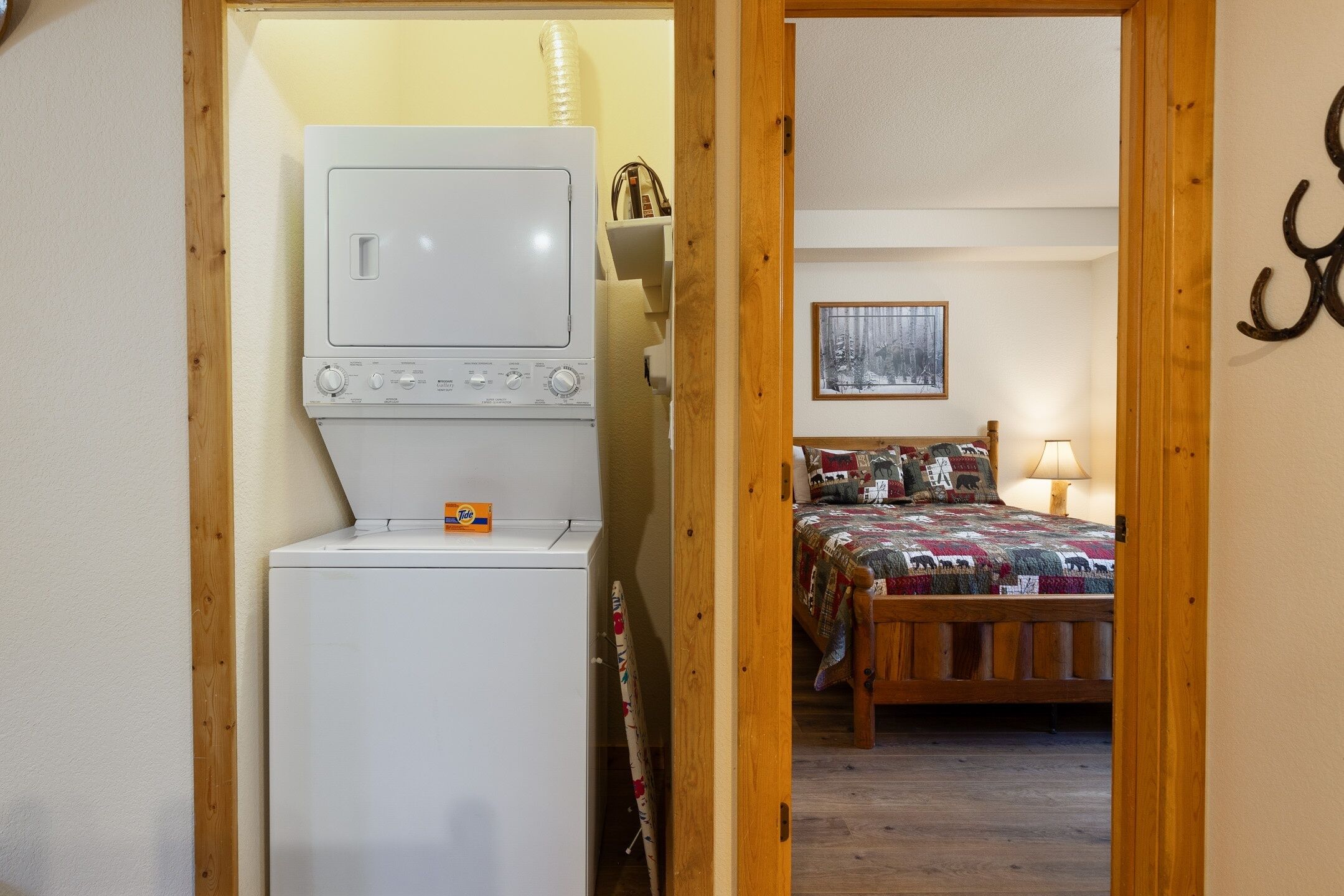 Una lavanderia con lavatrice e asciugatrice, un letto con copriletto e un quadro appeso al muro.