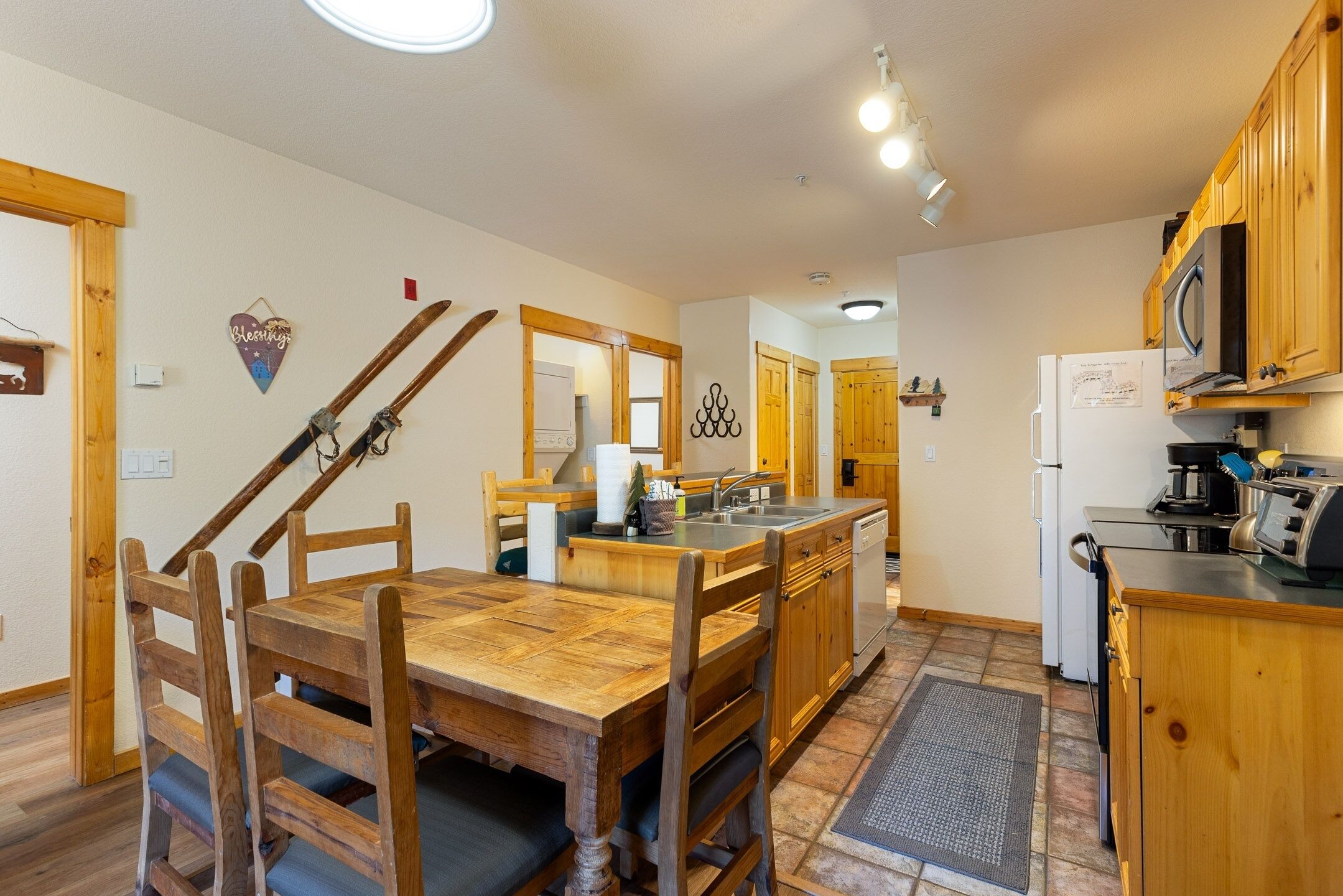 A kitchen with wooden cabinets, a central island, and a dining area with a wooden table and chairs.