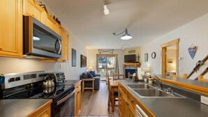 A kitchen with wooden cabinets, a built-in microwave, a stove, and a sink. - 2656 Tenderfoot Lodge 2 Bedroom Condo by RedAwning (Keystone)