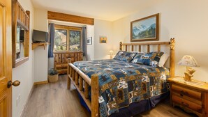 A bedroom with a wooden bed, a television, a window with a view of mountains, and a painting on the wall. - 2656 Tenderfoot Lodge 2 Bedroom Condo by RedAwning (Keystone)