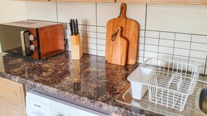 A kitchen with wooden cabinets, a toaster, a knife block, a wooden cutting board, and a dish rack. - Charming 2-bed Apartment in Stroud (Stroud)