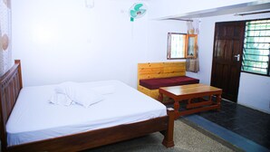 Une pièce comprenant un lit en bois, un banc en bois, une petite table, une fenêtre avec un rideau et une porte dotée d’un portail en métal.